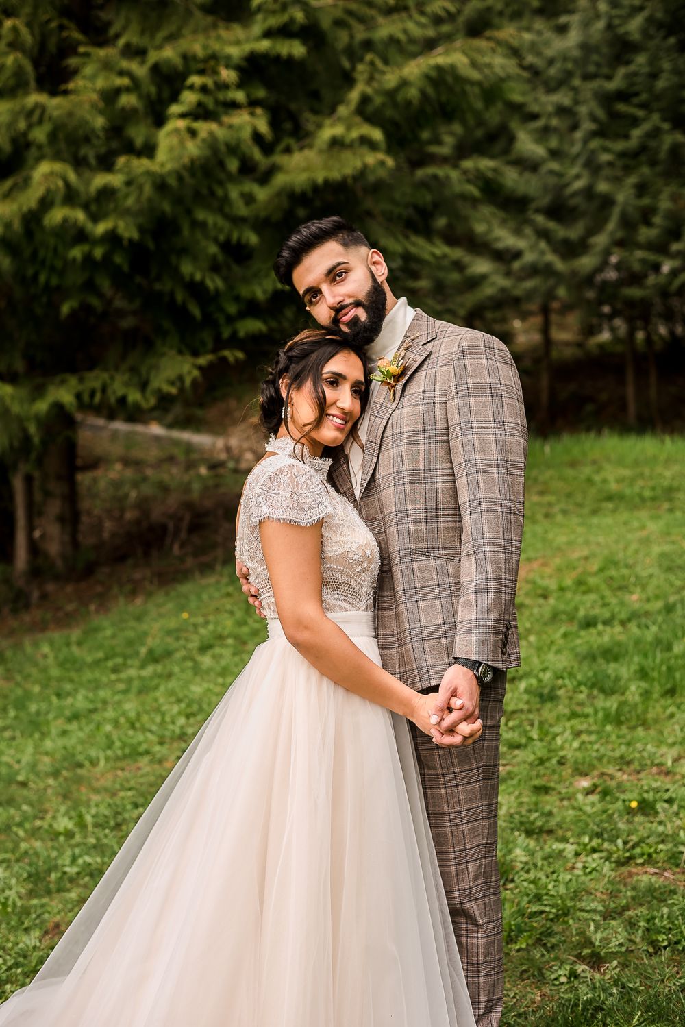 A bride and groom stand outside in the trees looking off into the distance together. Photo taken at the Greenhouse Venue in Abbotsford, BC.