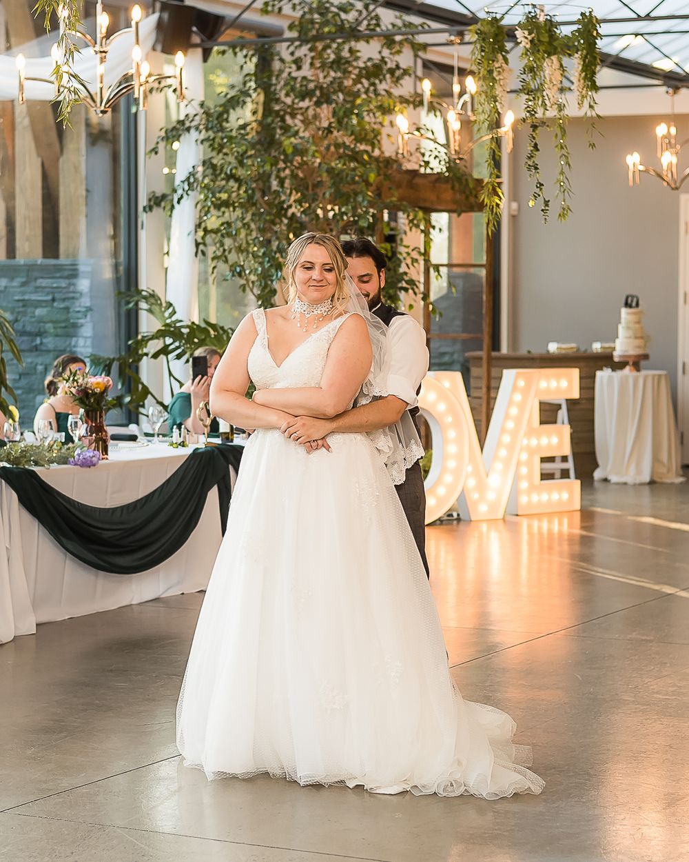A bride and groom enjoy their first dance together at their wedding reception. Soft lighting lights the dance floor.