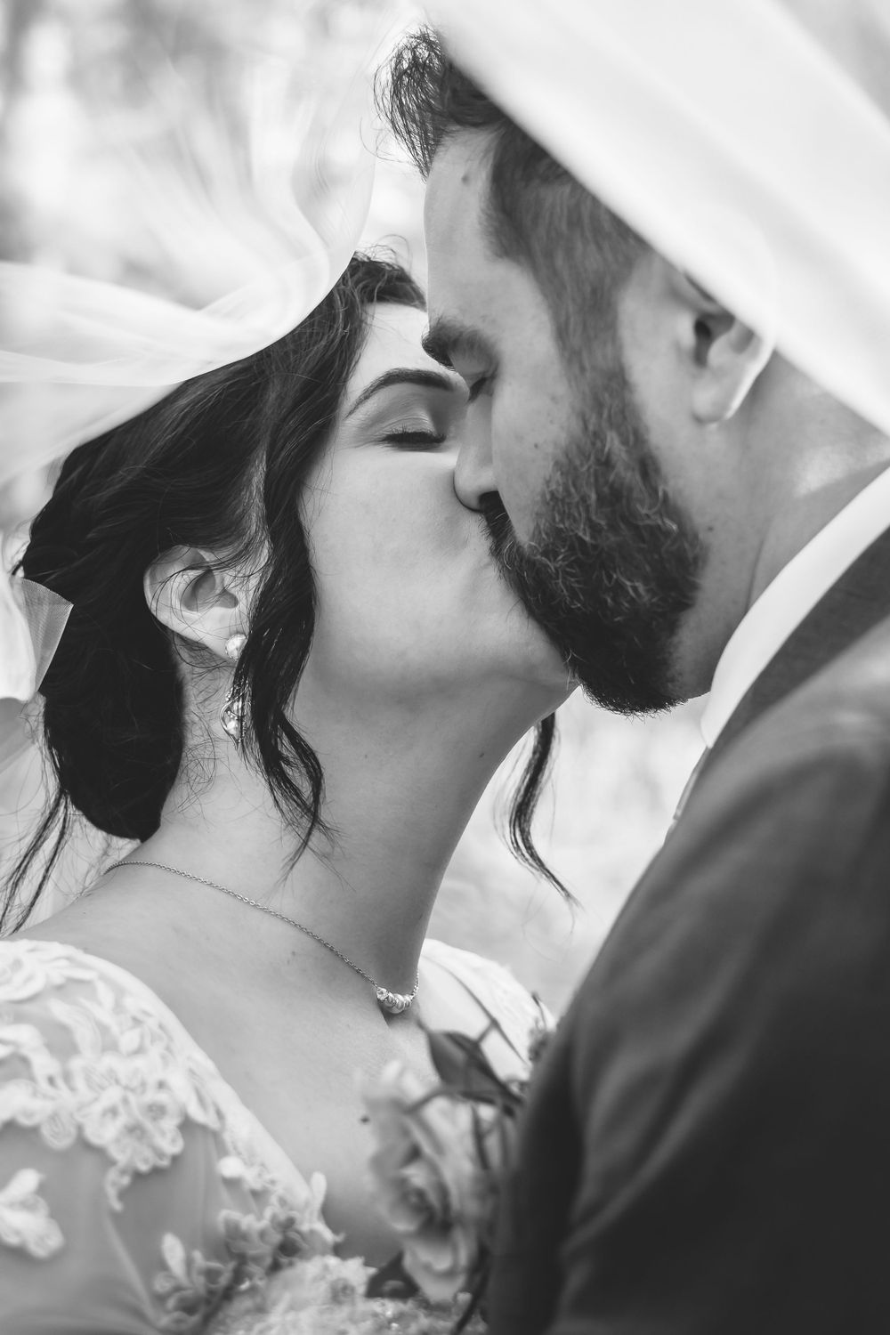 An under the veil photo as the bride and groom share a kiss.