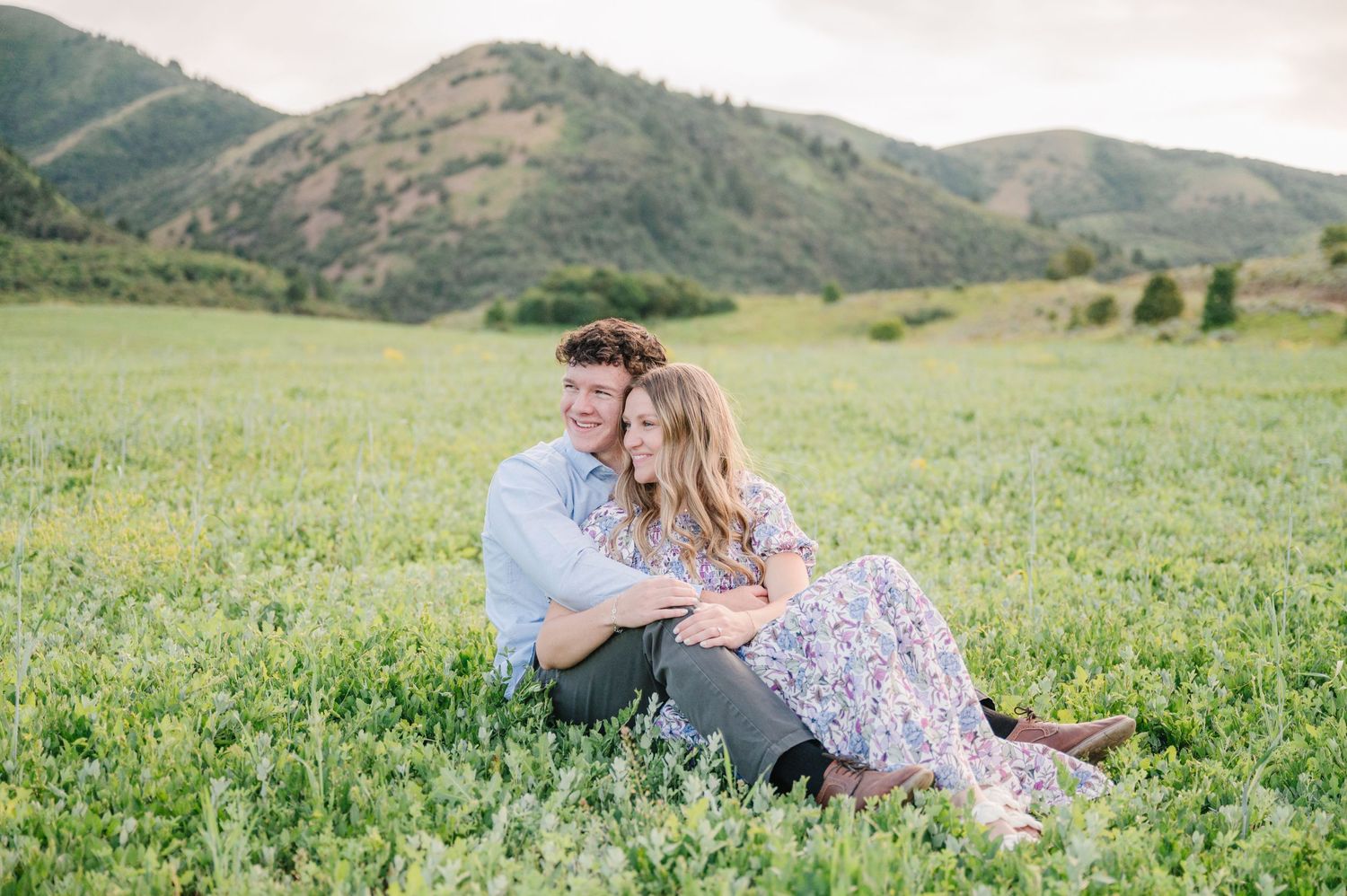 Happy couple relaxes together in a mountain meadow filled with wildflowers.