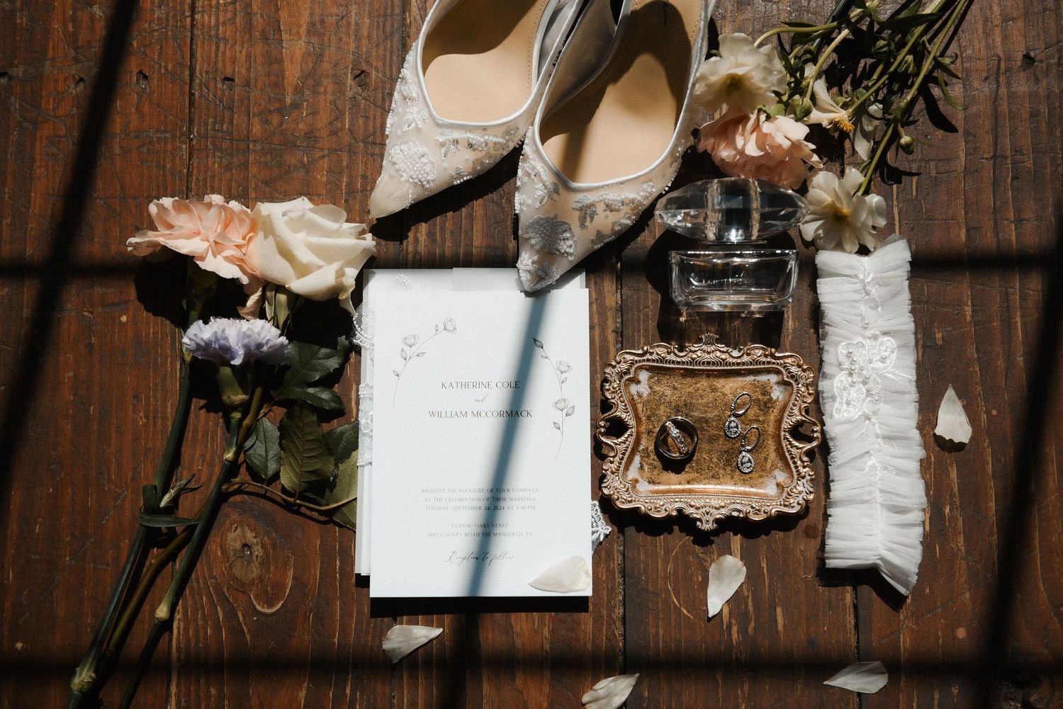 Wedding details flatlay with elegant bridal shoes, vintage camera, and decorative frame on rustic wooden surface.