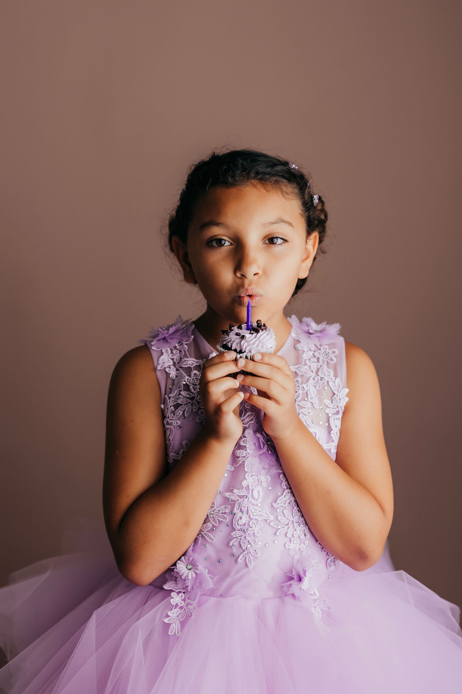 A child in a lavender tulle dress with lace details poses playfully in a studio photoshoot sequence.