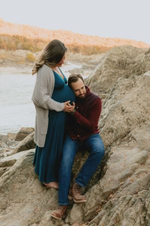 A tender maternity moment captured on rocky terrain at sunset.