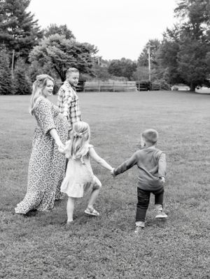 Black and white family portrait in an open field with trees in background.