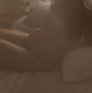 Intimate maternity boudoir photography in soft moody lighting.