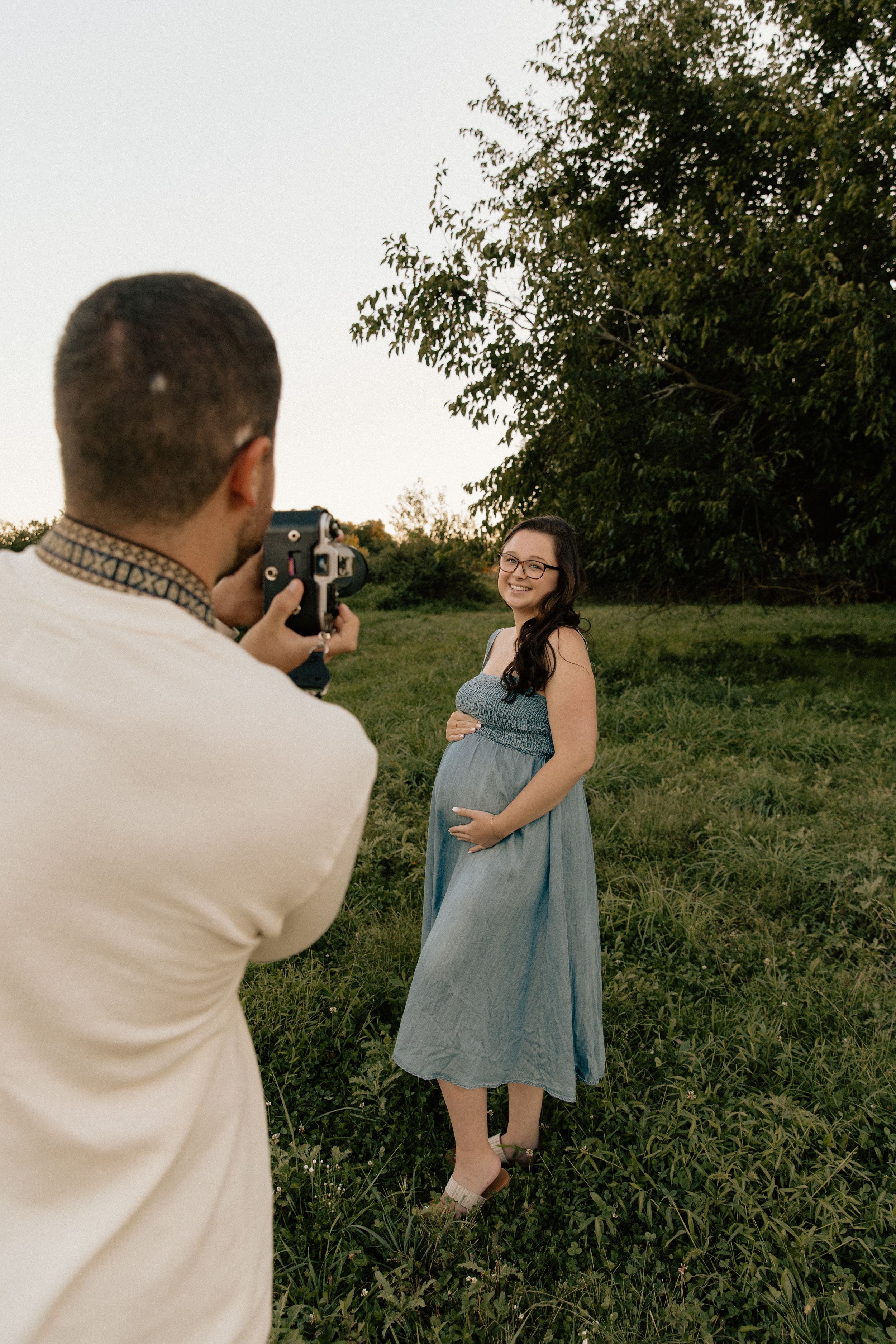 A photography session taking place in a green field during golden hour.