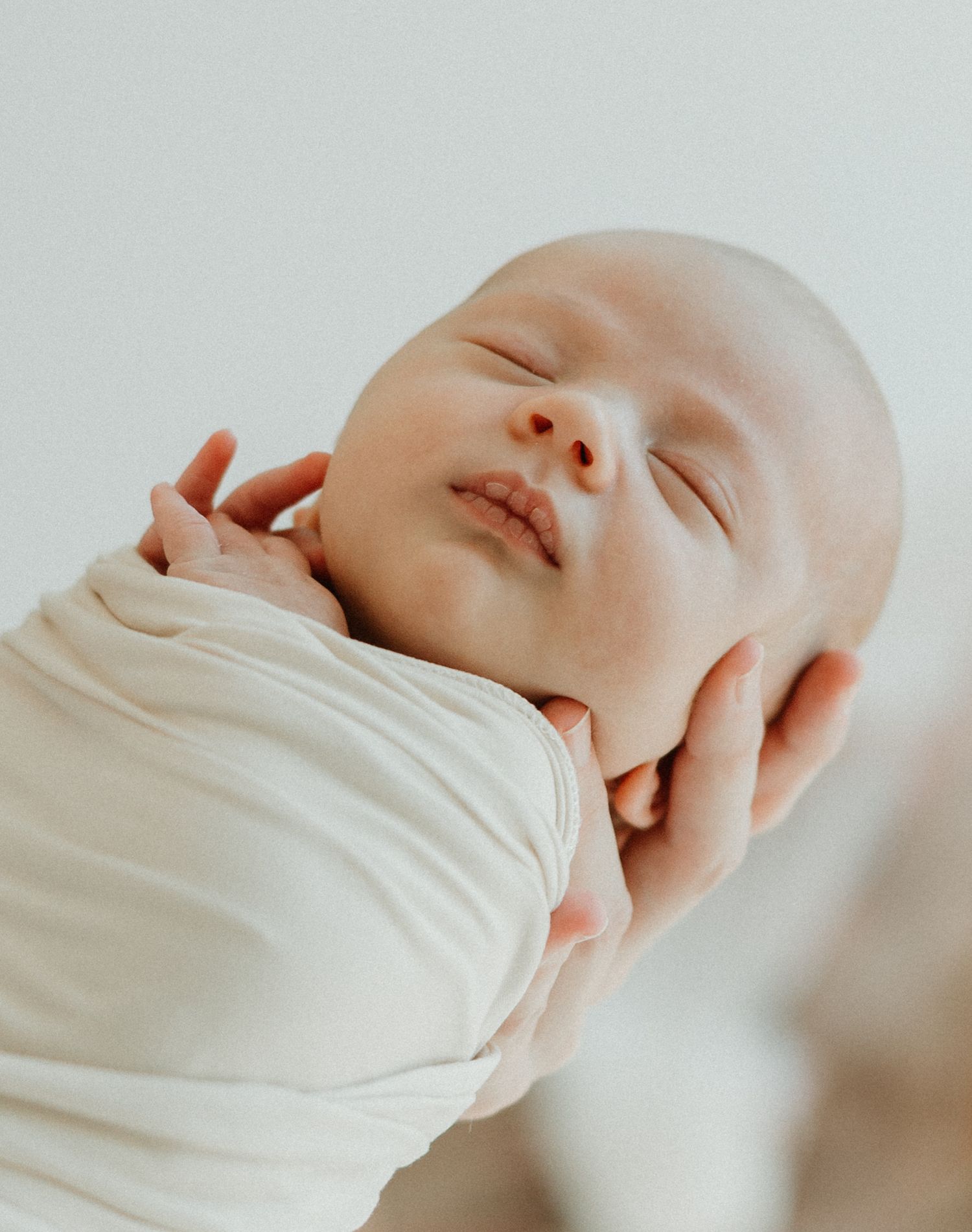 A tender moment of nursing captures a parent with floral arm tattoos feeding their infant in natural lighting.
