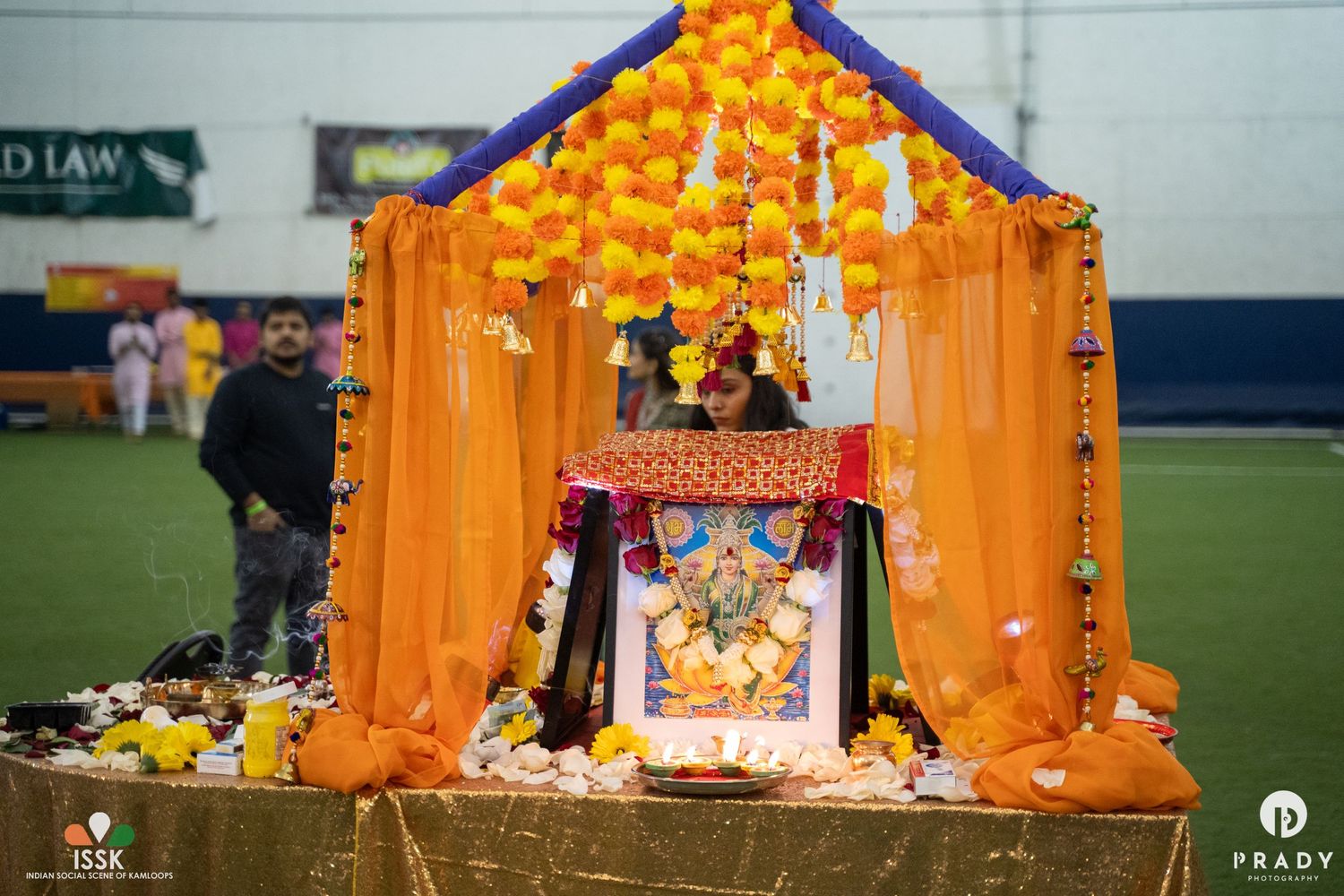 A decorative orange temple-style shrine with flowers and religious offerings on display.