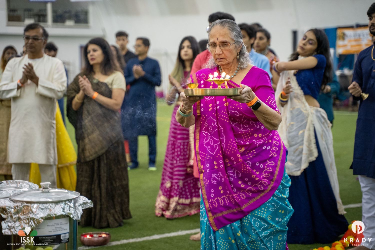 Attendees in vibrant traditional Indian garments participating in a cultural celebration indoors.