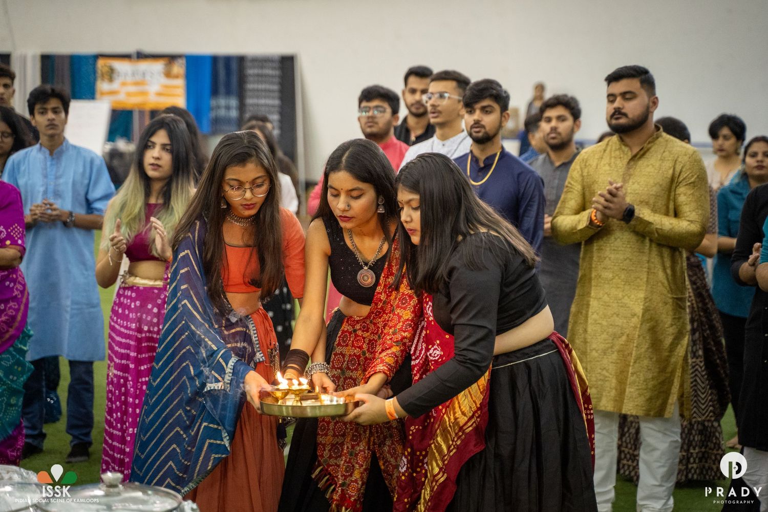 People in traditional Indian attire performing a ceremonial ritual with candles indoors.