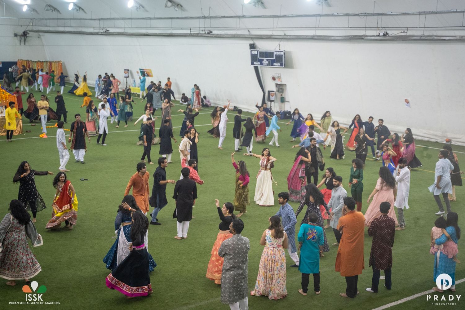 Crowd of people in traditional attire gathering on an indoor sports field for a cultural celebration.