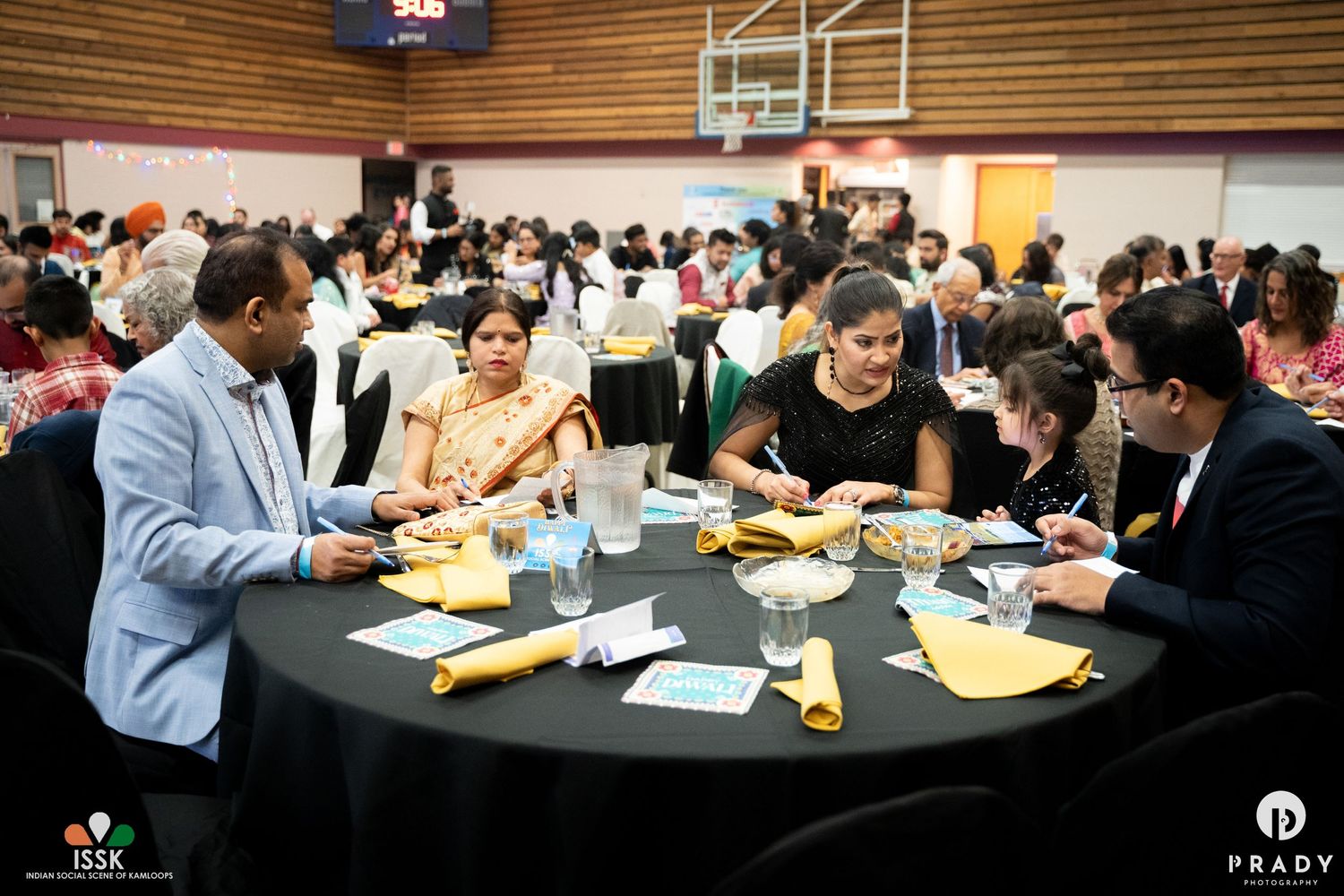 People dining at round tables during formal indoor banquet event.