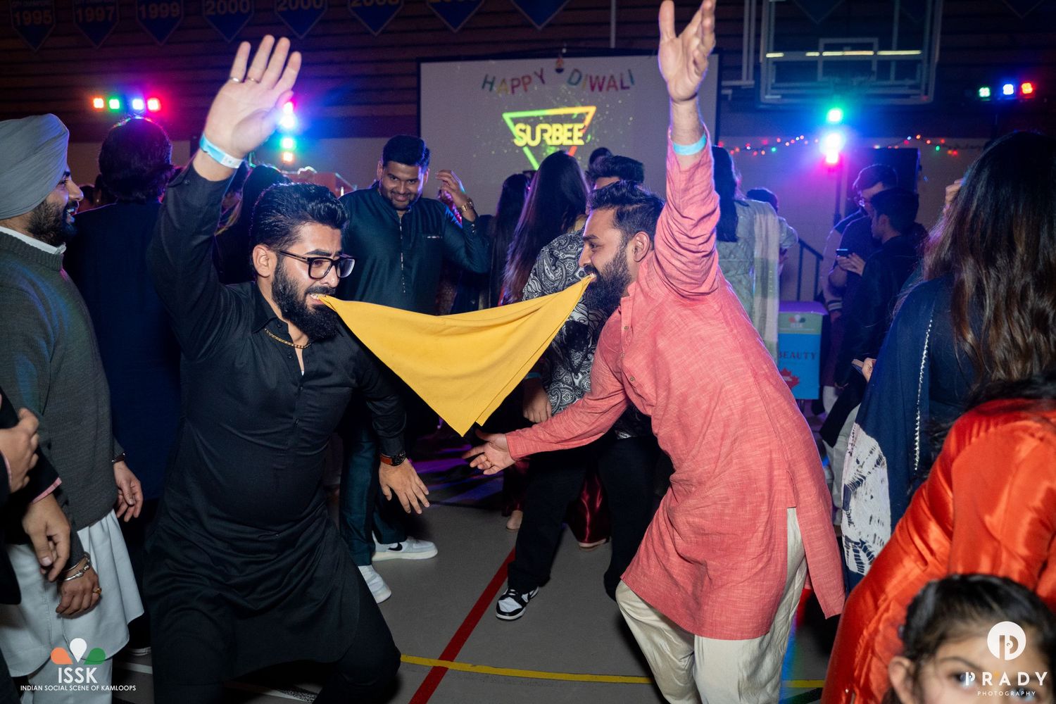 People dancing enthusiastically at a nightclub with colorful lighting and energetic atmosphere.