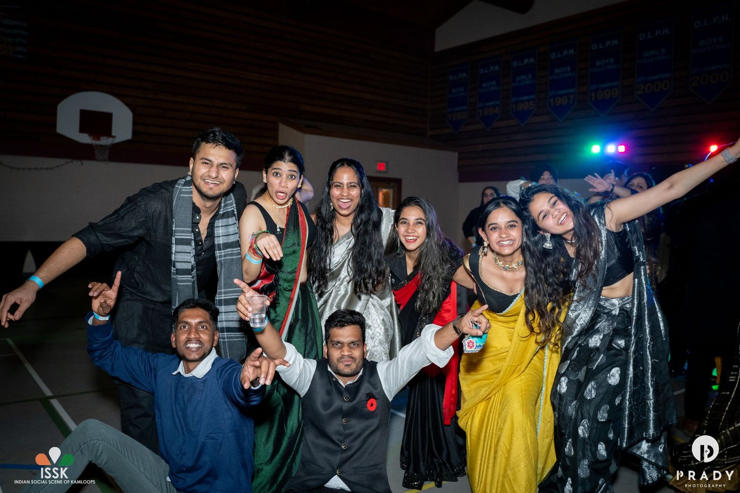 Group of friends celebrating at a party in traditional attire under colorful lighting.