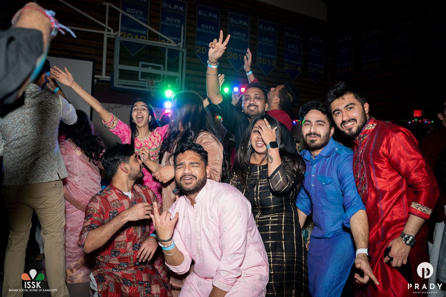 Enthusiastic crowd dancing and celebrating at a nighttime indoor party.