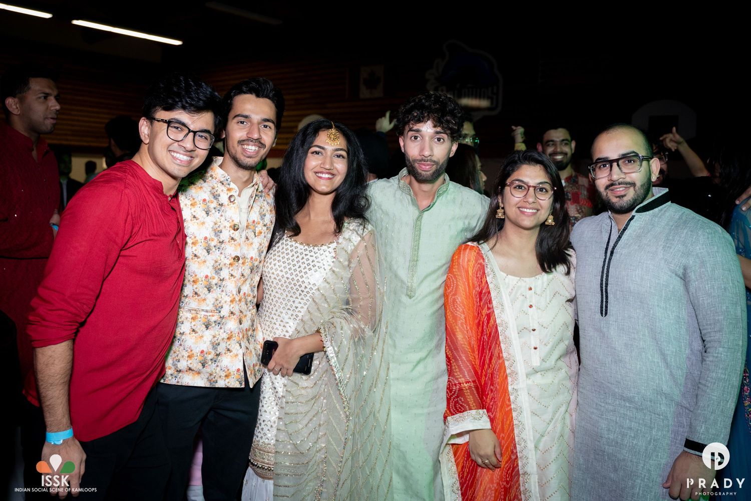 Friends in traditional Indian formal wear gathered at indoor event.