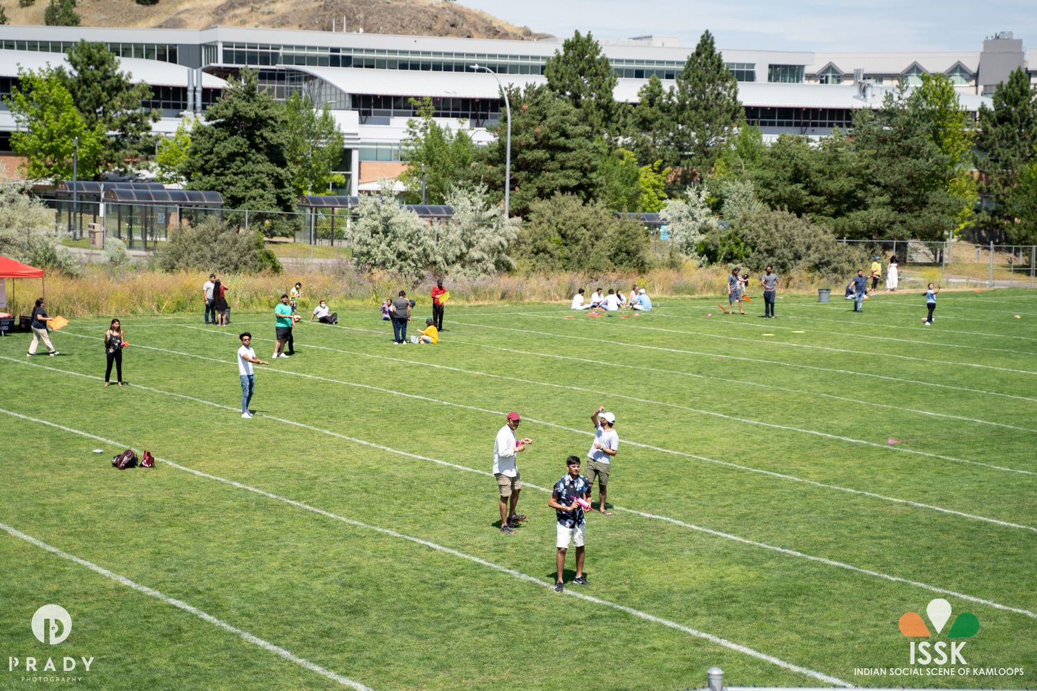 Aerial view of people playing sports on a green field near school buildings.