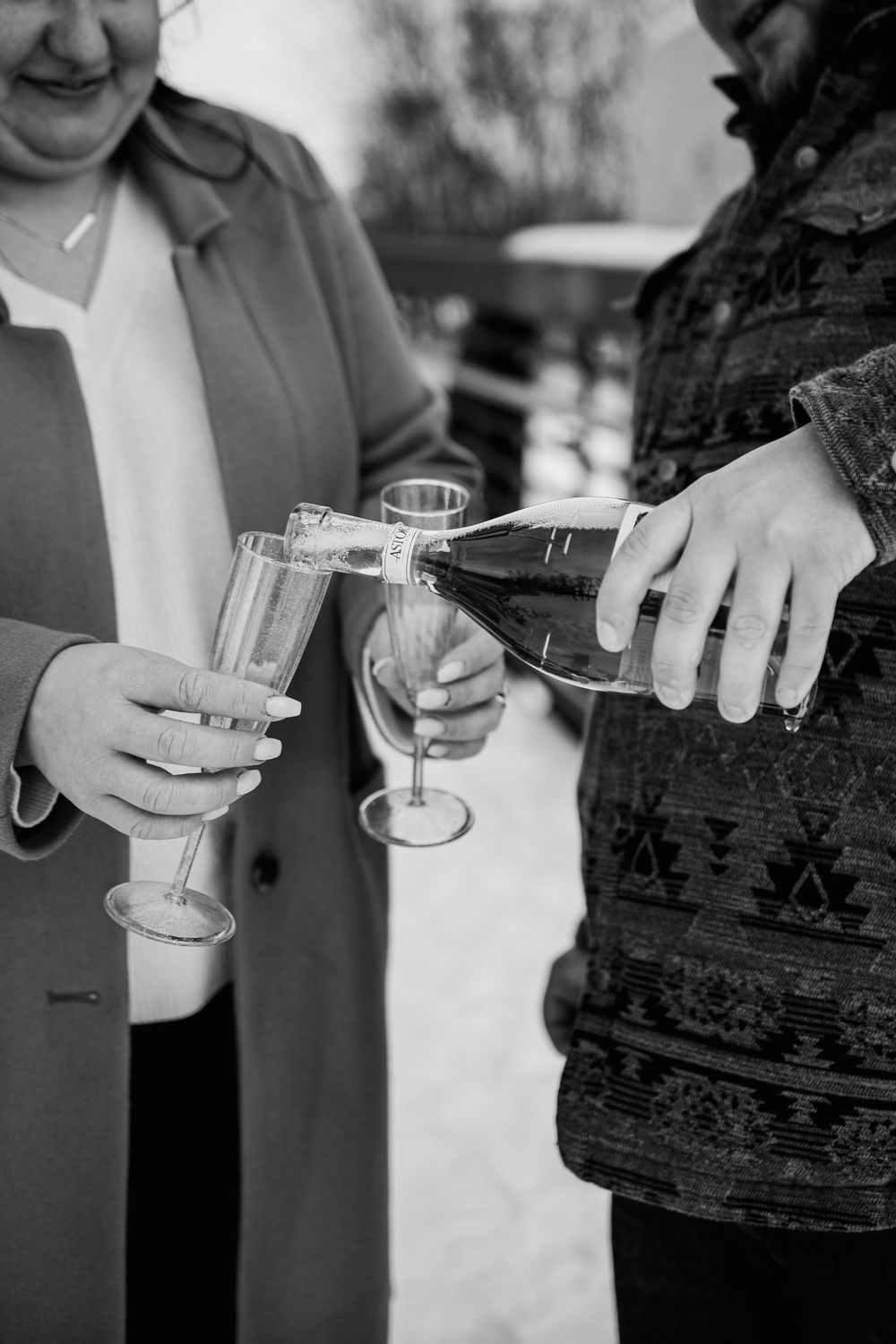 People hold shot glasses filled with clear liquid during a celebratory toast at a social gathering.