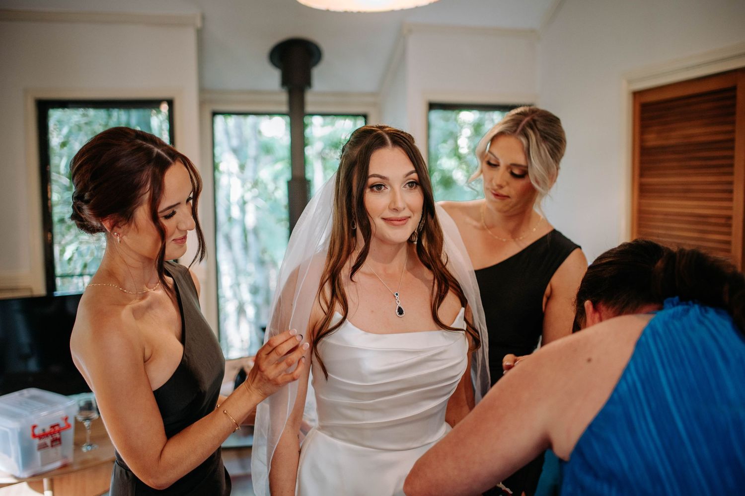 Wedding preparation scene with the bride being helped into her dress by attendants.