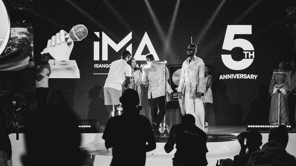 Performers on stage during IMA's 5th anniversary celebration in black and white monochrome lighting.