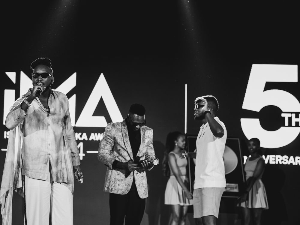 Wide shot of performers on stage during IMA anniversary event with dramatic lighting.