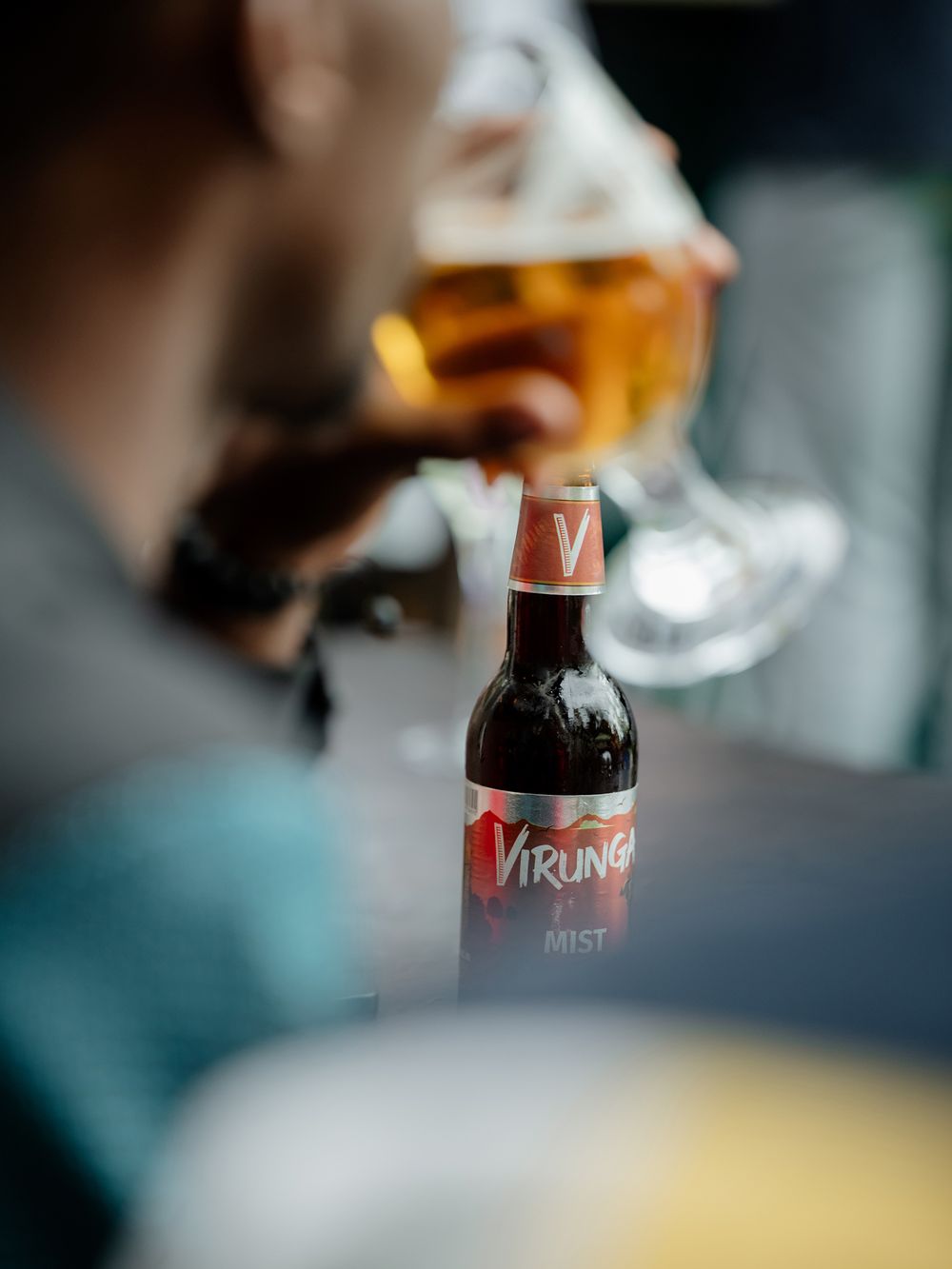 Close-up of a Virung bottle with blurred glass of amber liquid in background.