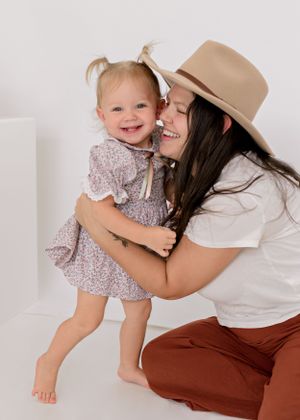 Joyful family moment with parent in tan hat and child in floral dress.