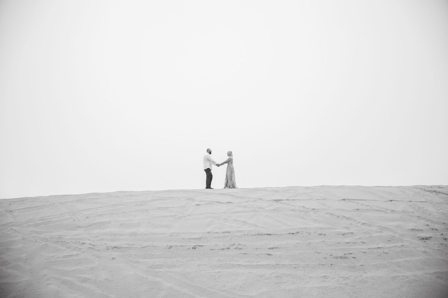 Minimalist black and white photo of two people standing on hilltop.