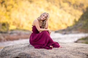 Elegant portrait session in a burgundy dress against golden autumn foliage at sunset.