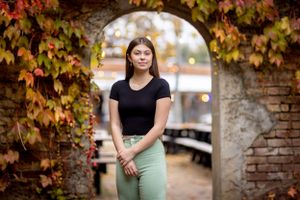 Outdoor autumn portrait with brick wall backdrop and colorful fall foliage.