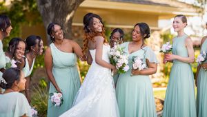 Bridesmaids in mint green dresses pose together during an outdoor wedding celebration.