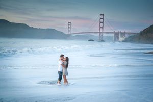 A romantic beach photoshoot near the iconic Golden Gate Bridge in San Francisco during sunset.