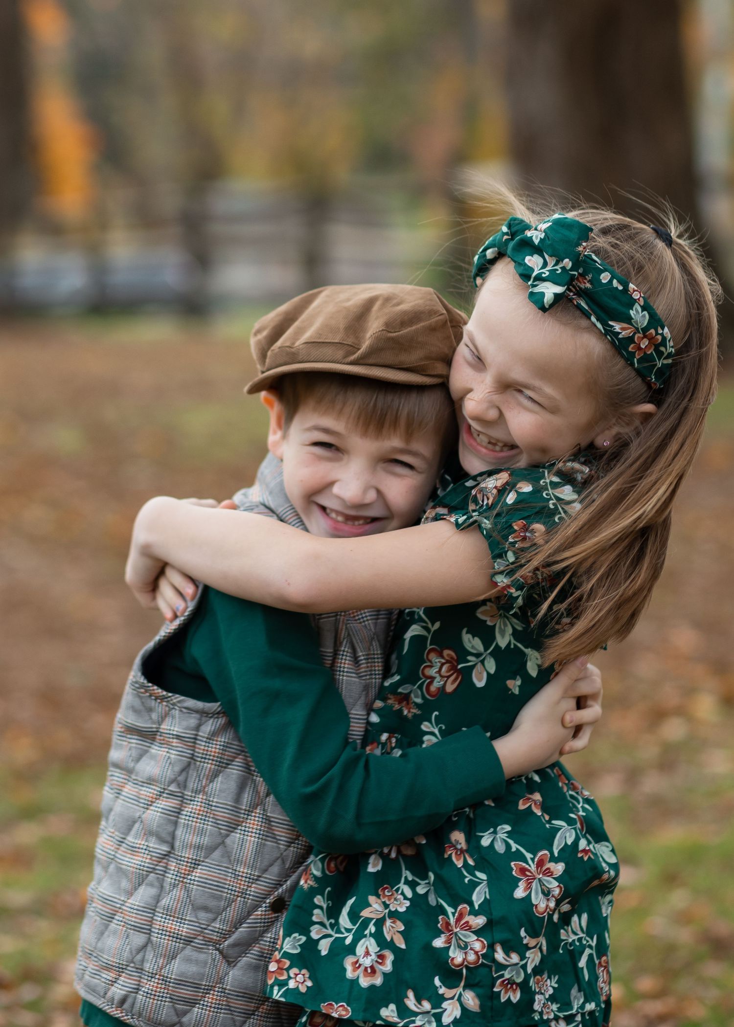Siblings share a heartwarming embrace outdoors during autumn with fallen leaves on the ground in Lincoln Park, Lincoln, Rhode Island, USA.