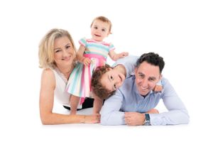 Joyful family lying together on white background for studio portrait.