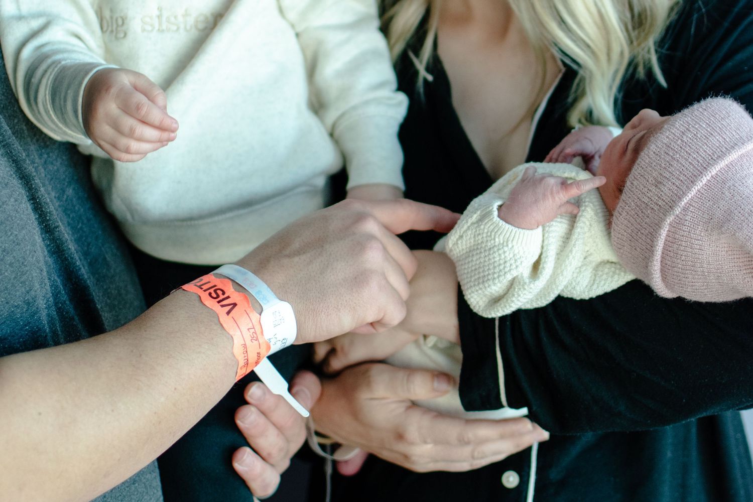 Hospital ID bracelet being placed on tiny newborn hand.