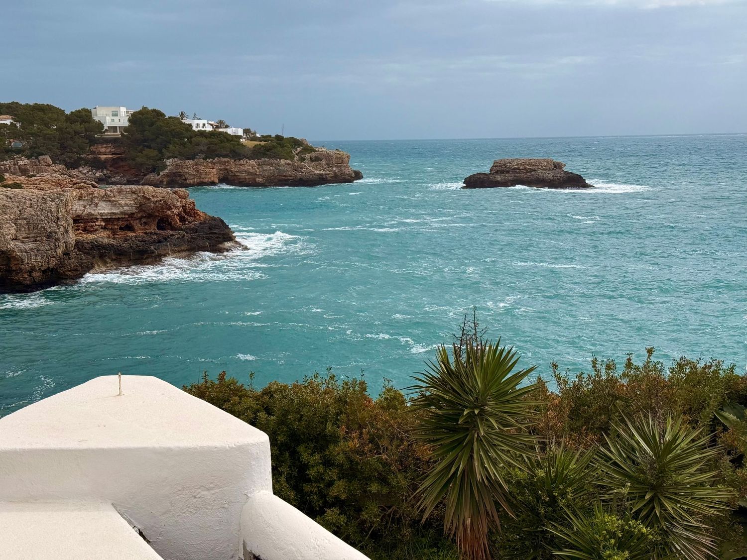 Beautiful residential properties nestled in hills above Mediterranean coast during dramatic sunset.