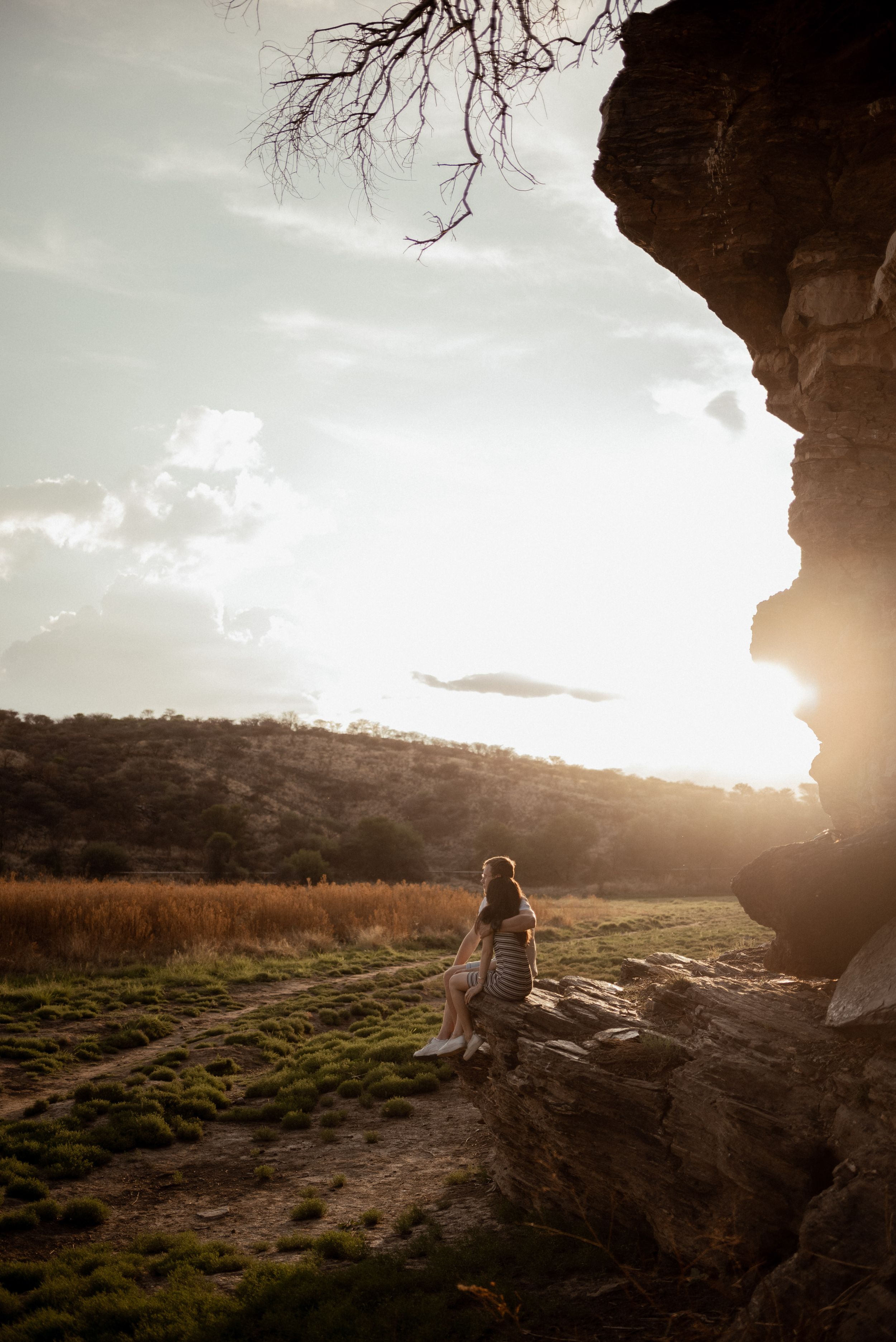Silhouette of a dress flowing in the wind near rocky outcrop during golden sunset.