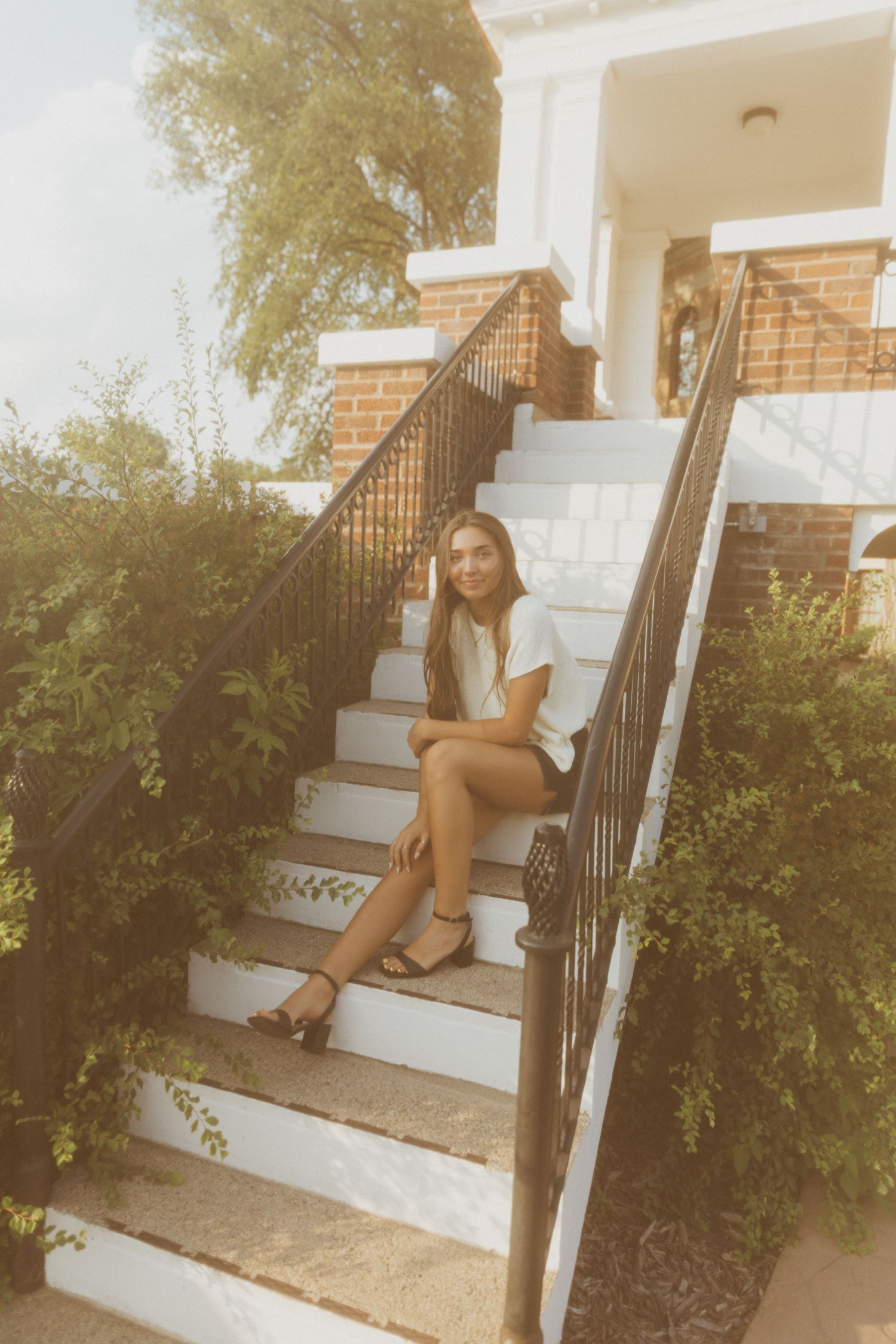White concrete steps with wrought iron railing against a brick building exterior.