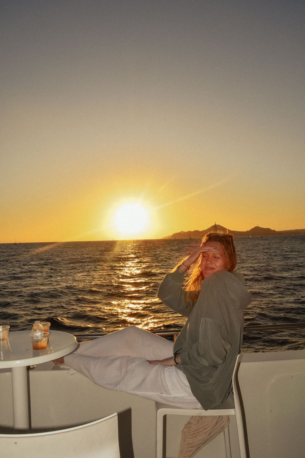 Beautiful ocean sunset view from a boat deck with golden light reflecting on water.