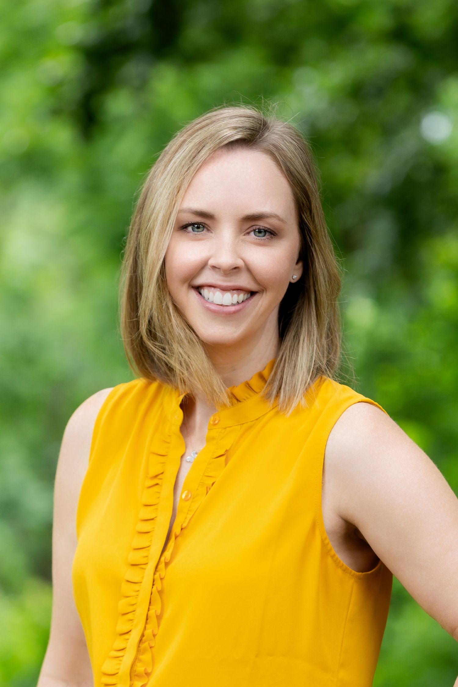 Outdoor portrait series showing bright yellow sleeveless top against leafy green background.