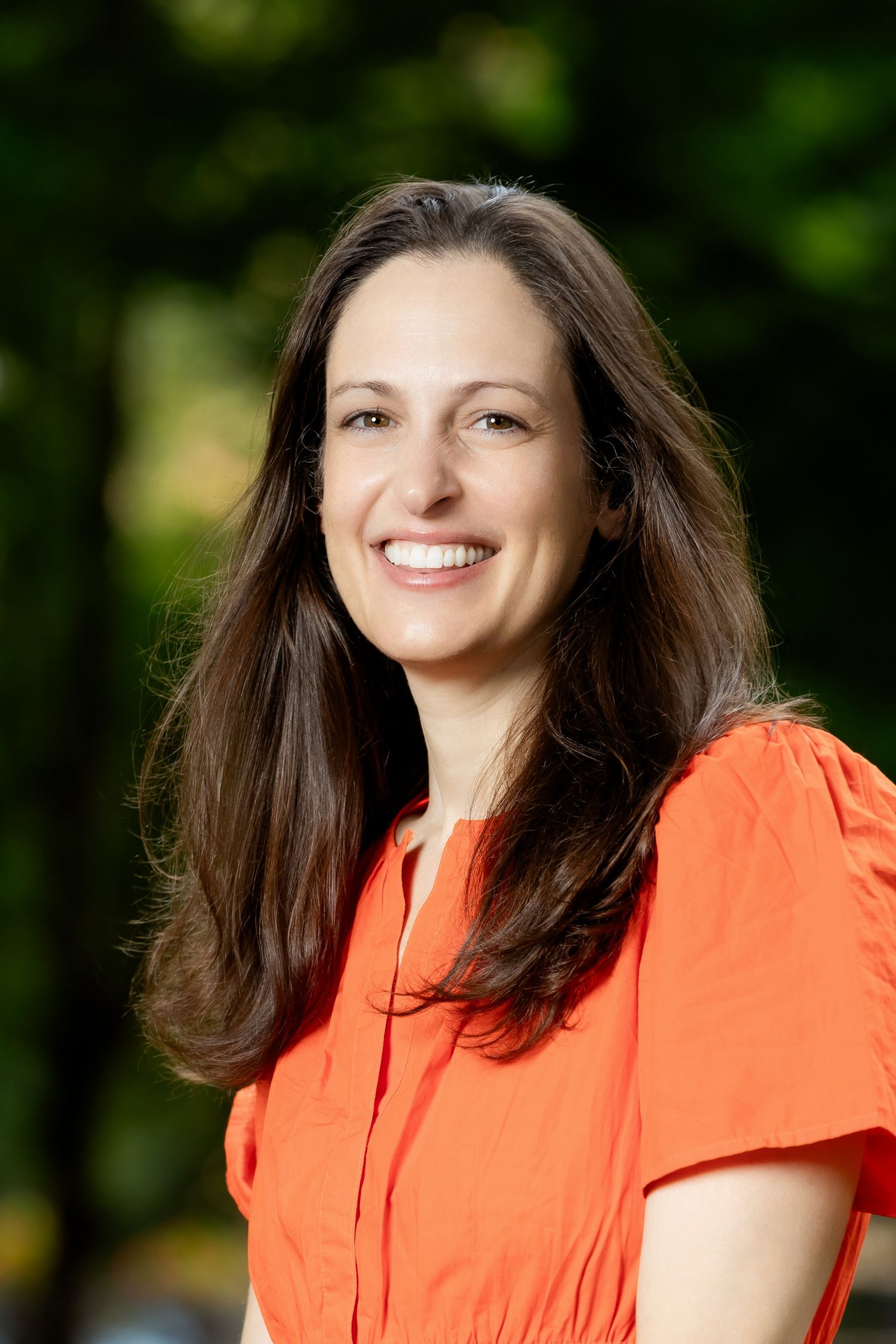 Outdoor portrait series featuring coral colored top and long dark hair with natural background.