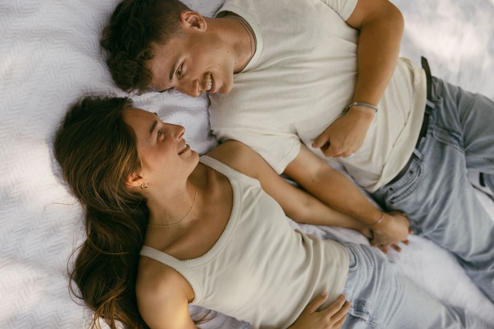 Person sleeping peacefully in cozy white bedding with gray pillows and natural lighting.