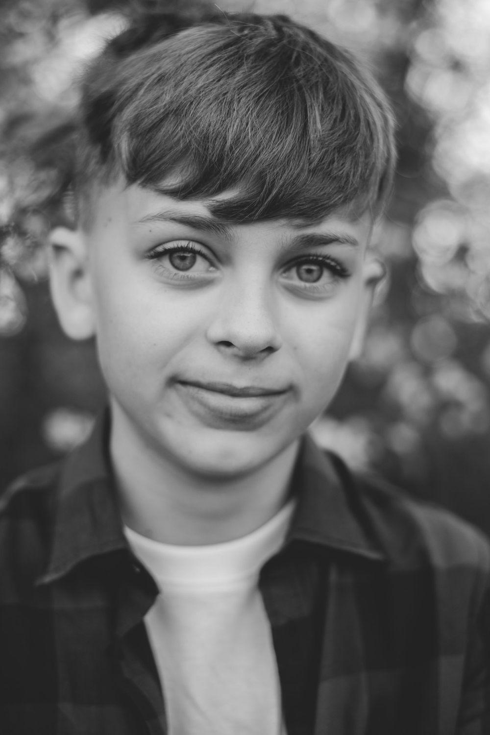 Close-up black and white portrait of youth wearing casual shirt outdoors.