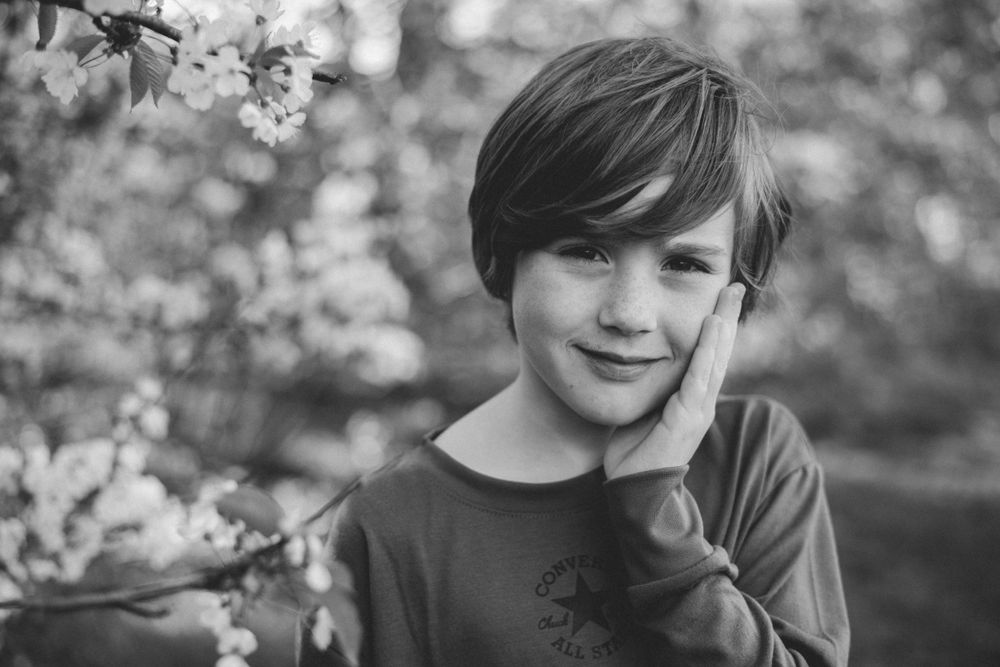 Black and white portrait with spring blossoms in soft focus background.