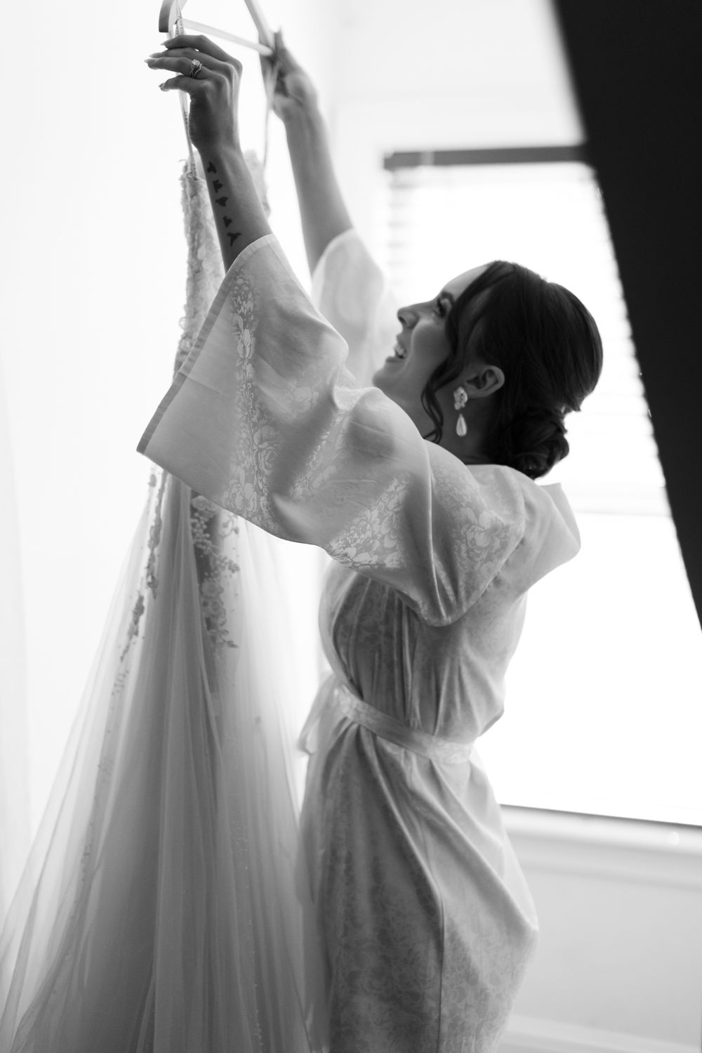 Silhouette of person preparing wedding dress in morning light.