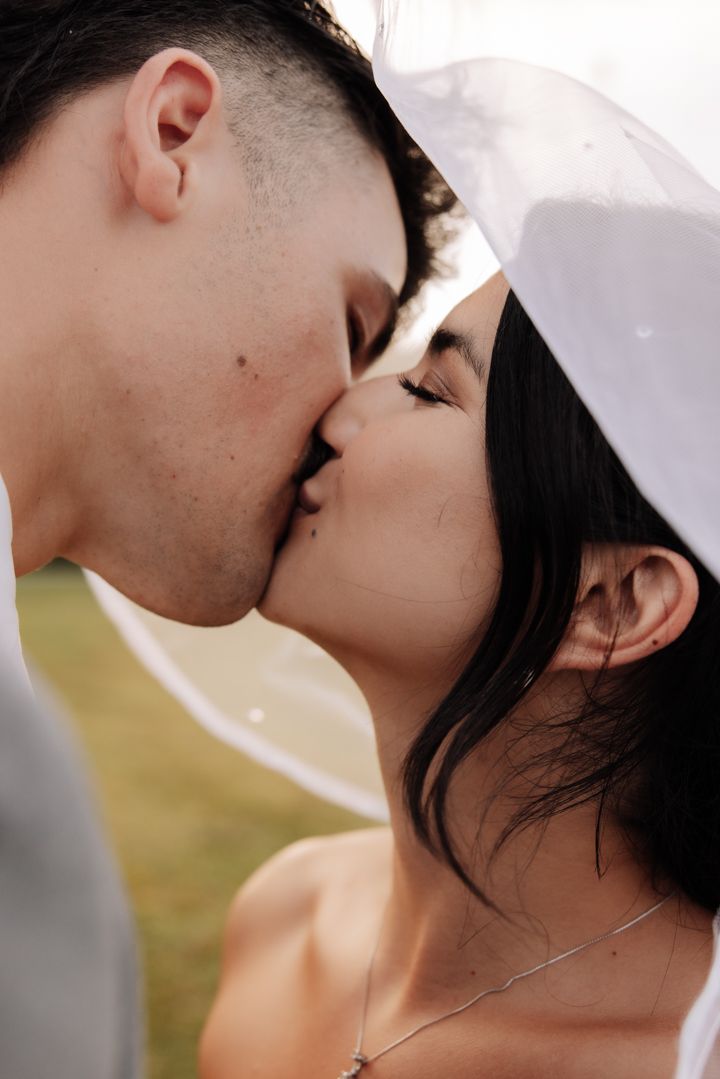 A tender wedding kiss captured in close-up with soft light and a romantic atmosphere.