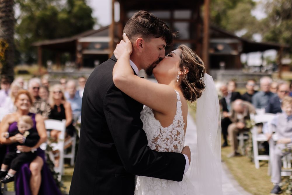 Newlyweds share their first kiss as married couple during outdoor wedding ceremony. wedding ceremony at the barn at cottonwood ranch florida