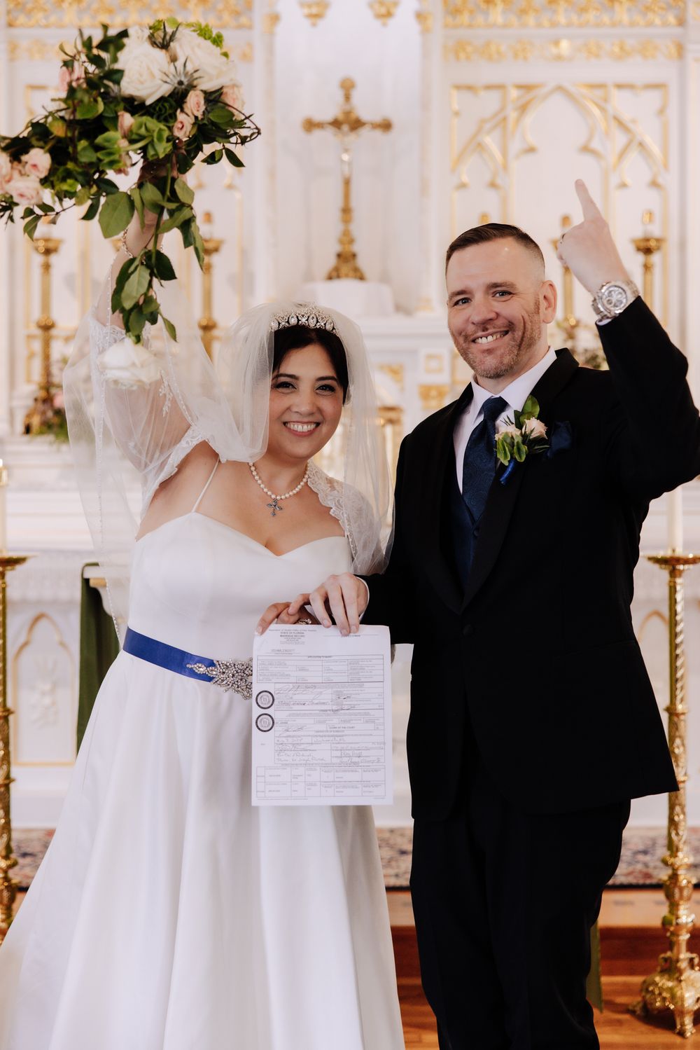 Wedding celebration in an ornate church with decorative floral arrangements.