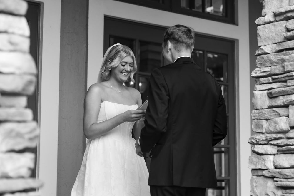 A black and white wedding moment captured between a couple during their first look outside a stone building entrance.