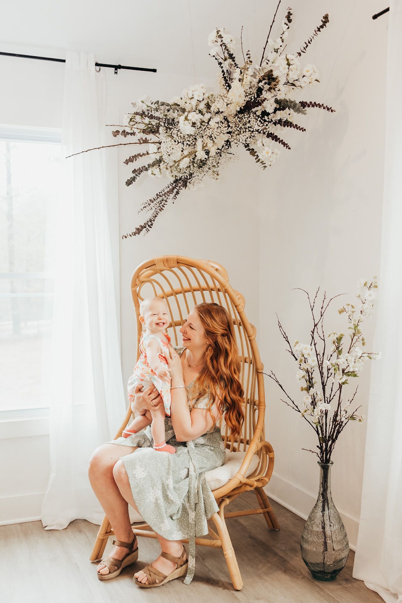 mom with long red hair holding her baby in a peacock chair